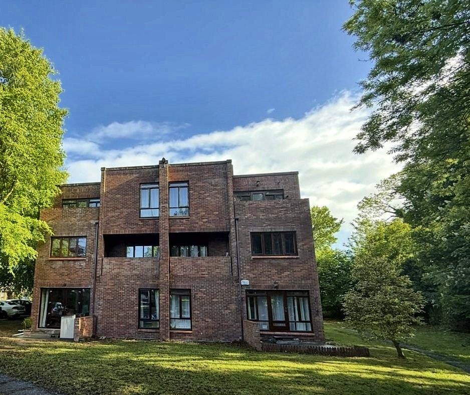 The Moorings apartment block on a summer afternoon, with mature trees on either side