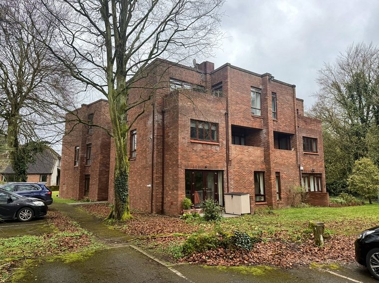 The apartment block seen from the car park, with bare winter trees around it